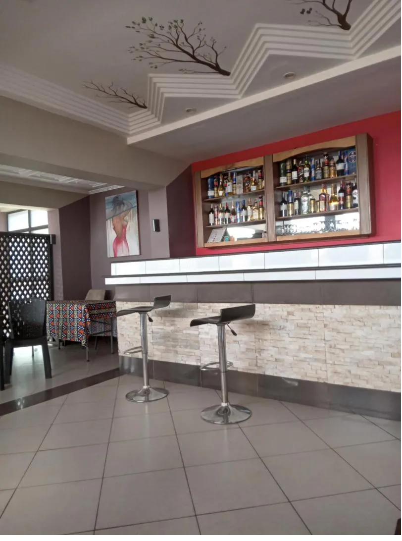 Bar de la résidence avec comptoir en pierre et étagères garnies